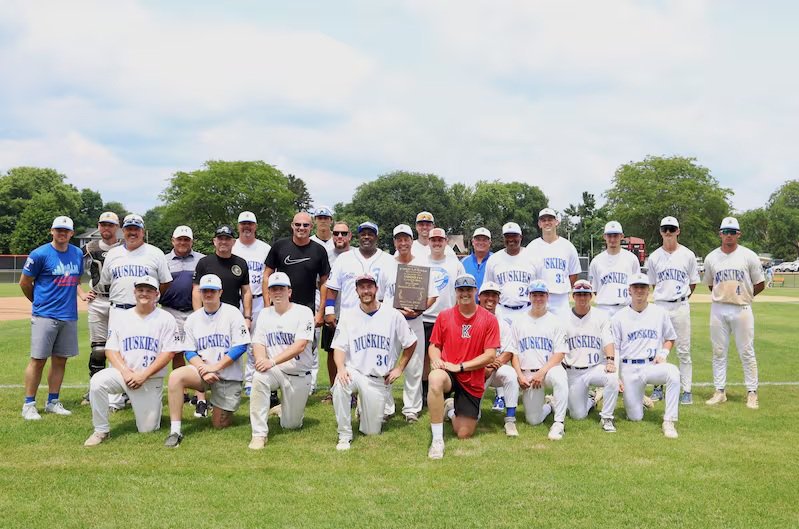 Current and former members of the Beecher Muskies surround manager Fred LeSage, center, after a ceremony celebrating LeSage's 1000th career win before