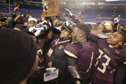 Douglass High School football coach J.C. Pinkney holds the 2A state championship trophy Saturday after defeating Dunbar.  Bill Ryan/The Gazette